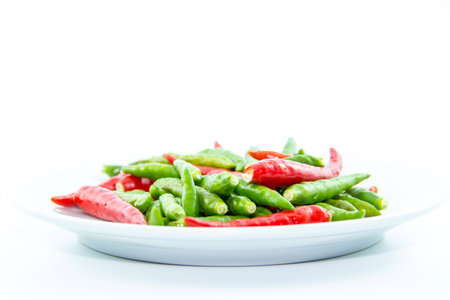 Red and green cayenne peppers on white plate on white backgroundの写真素材