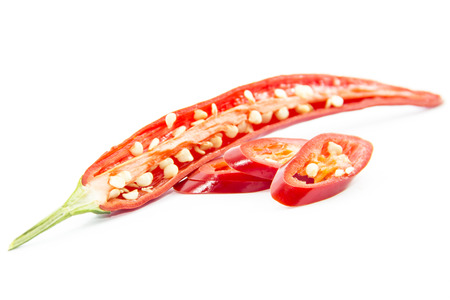 Sliced half and pieced of red chili pepper ingredient on white backgroundの写真素材