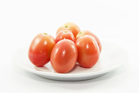 Fresh tomatoes on white plate and white backgroundの写真素材