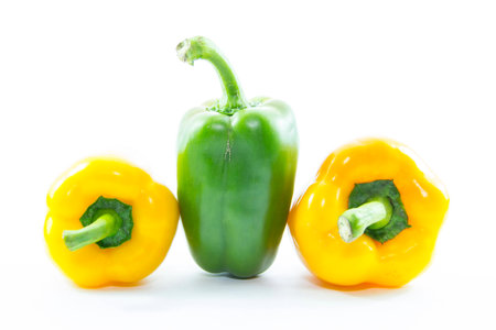 Green chili capsicum between yellow on white background