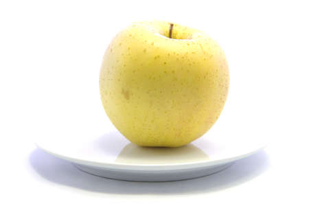 Fresh yellow apple healthy fruit on white plate and white backgroundの写真素材