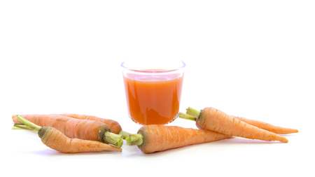 Baby carrots juice shot glass with raw recipe on white backgroundの写真素材