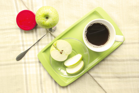 Green Apple with a cup of coffee on table mat backgroundの写真素材