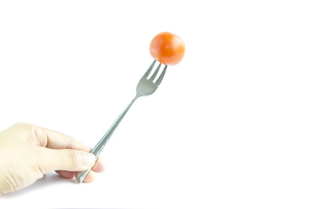 Fresh red tomato with fork by hand on white backgroundの写真素材