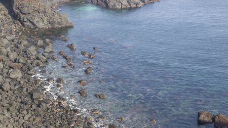 Black rock contrast with  transparent deep blue ocean backgroundの写真素材