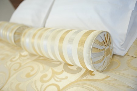 Decorative pillow-cushion of golden fabric on the bed. Element of luxury interiorの写真素材
