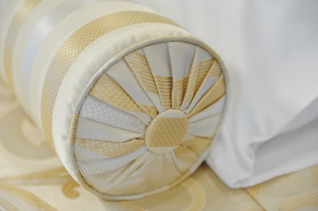 Decorative pillow-cushion of golden fabric on the bed. Element of luxury interiorの写真素材