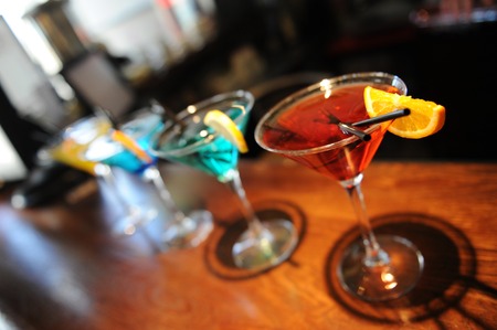 Four colored stay cocktails on the bar. Yellow, blue, turquoise, red. Decorated with a lemon slice