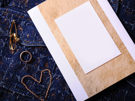 Gold jewelry and certificate with empty blank for design on a blue denim background. Ring, brooch in the form of cat, bracelet chain lies like heart.の写真素材