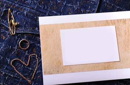 Gold jewelry and certificate with empty blank for design on a blue denim background. Ring, brooch in the form of cat, bracelet chain lies like heart.の写真素材
