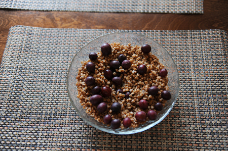 A large glass bowl of boiled buckwheat with grapes gooseberry on serving napkinの写真素材