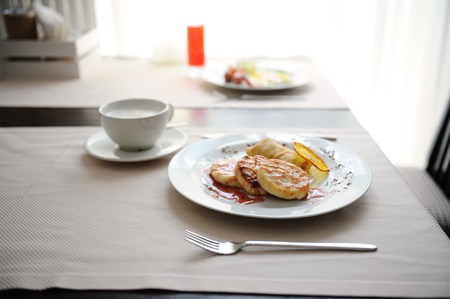 Served breakfast in the restaurant. Cottage cheese pancakes with orange ringlets with coffeeの写真素材