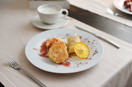Served breakfast in the restaurant. Cottage cheese pancakes with orange ringlets with coffeeの写真素材