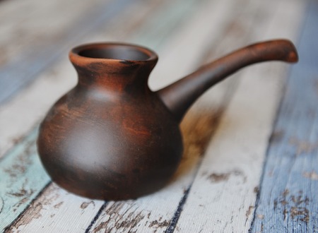 Clay ceramic cezve handmade. Pottery for turkish coffee. Wooden backgroundの写真素材