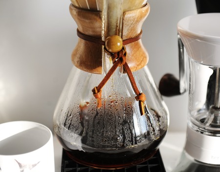 Freshly brewed drip coffee close up in sun rays. Manual coffee grinder