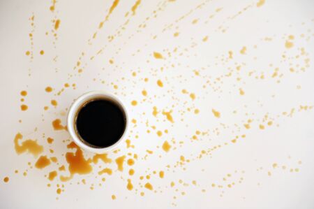 Cup of espresso on a white surface splattered with drops of coffee. Background, free space for textの写真素材