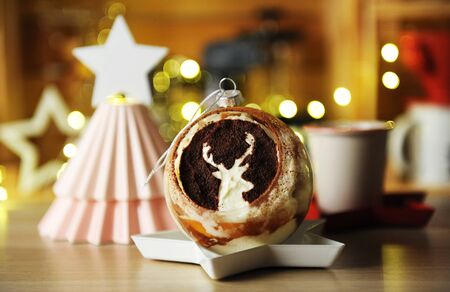 Tiramisu served in glass bowl like a Christmas tree ball with deer image. Blurry lights in the backgroundの写真素材
