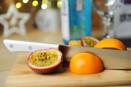 Making cocktail or dessert. Passion fruit and orange on cutting board with knife.