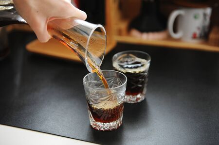 Pouring black filter coffee from decanter into glasses. Manual brewing still life. Third wave...