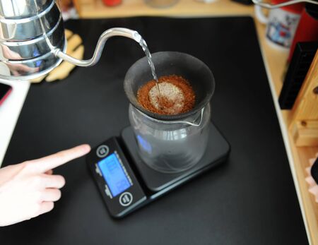 Black porous ceramic paperless coffee dripper filter on the glass jug. Gooseneck kettle. Electronic scale. Manual brewing still life.の写真素材