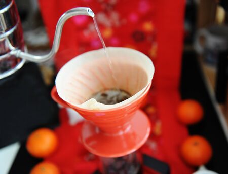 Chinese coffee still life. Manual brewing coffee in red dripper pour over. Traditional fabric...