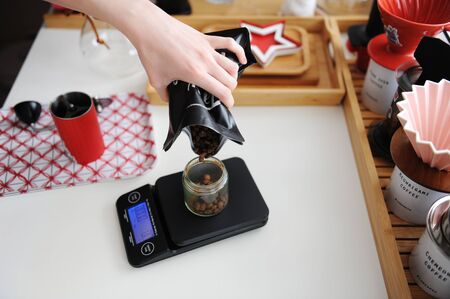 Alterantive brewing still life. Pour coffee beans into manual grinder on electronic scale. Third...