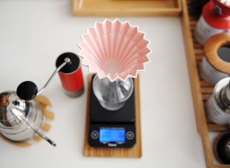 Alternative manual brewing. Pink ceramic origami dripper with paper wave filter. Top view. Red...