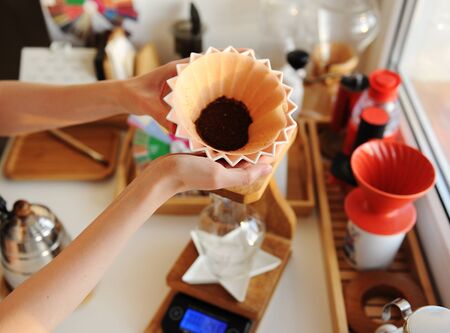Pink ceramic origami dripper on wooden drip station on scale. Manual brewing still lifeの写真素材
