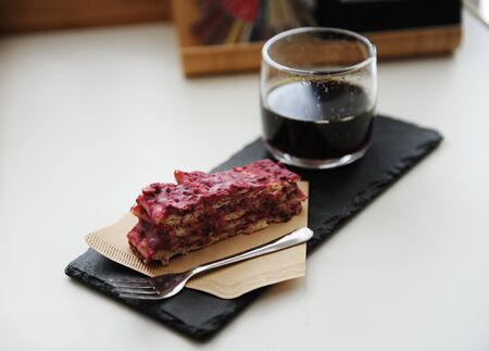 Served black coffee and dessert. Slate board, vegan cake Napoleon Millefeuille on a paper coffee...