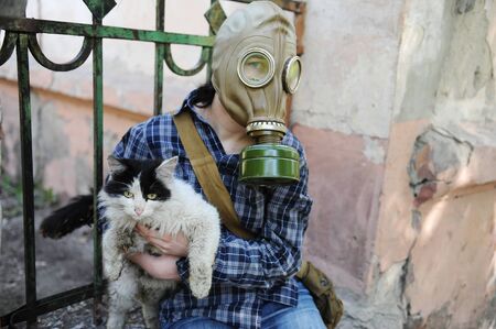 A man in a gas mask holds a cat in his handsの写真素材