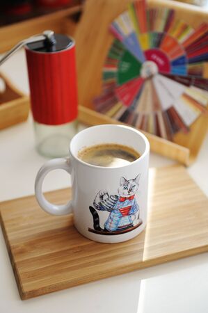 Freshly brewed coffee in mug with cat barista. Manual grinder and taste wheelの写真素材