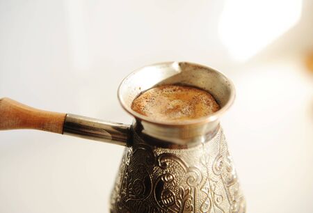 Brewing turkish coffee in cooper cezve close up. White background isolatedの写真素材