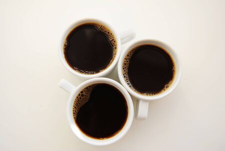 Black coffee in three white cups on white background top viewの写真素材