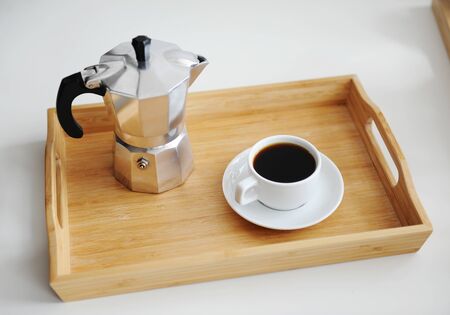 Italian coffee espresso maker moka pot and white cup of coffee on bamboo wooden tray. White backgroundの写真素材