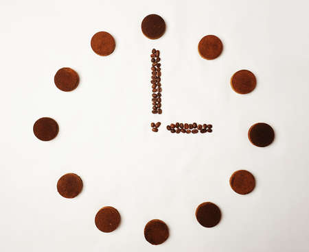 Clock laid out of espresso coffee pucks and roasted beans on white background. Isolated, top viewの写真素材