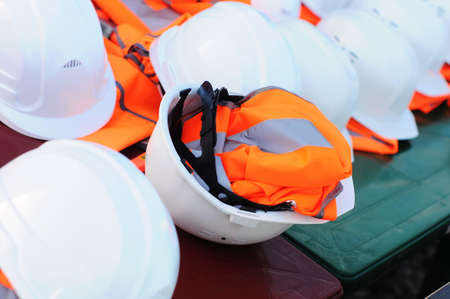 Sets of white construction helmets and orange vests at a construction site, no peopleの写真素材