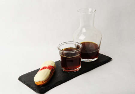 Freshly brewed black coffee served in glass carafe on slate board with french dessert eclair. White...