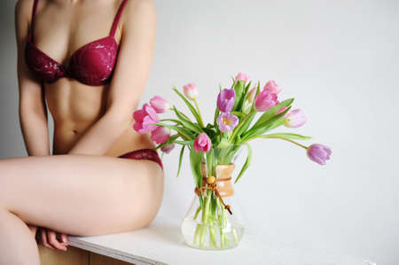 Tulips in a glass coffee decanter and a beautiful girl in lingerie. Spring coffee vibesの写真素材