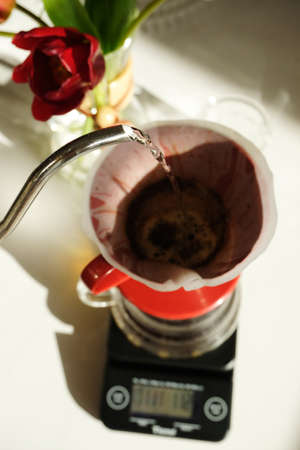 Manual pour over coffee brewing. Water pouring from gooseneck kettle. Red v60 dripper, electronic...