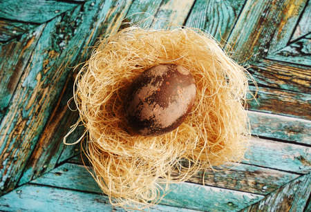 Brown marbled Easter dyed egg on coconut palm fiber on a turquoise wood background, top viewの写真素材