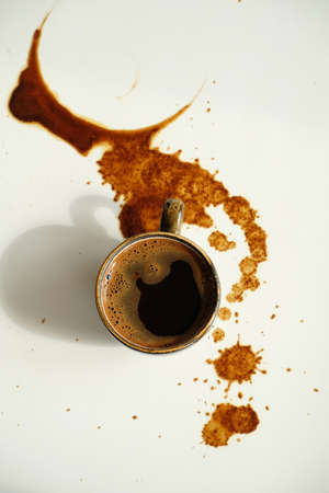 Cup of espresso on spilled coffee spots on white background top viewの写真素材