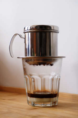 Making coffee in a Vietnamese phin with condensed milk in a glass.