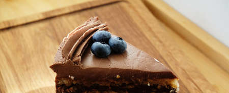 Kiev cake with chocolate icing and blueberries, closeup. Horizontal banner