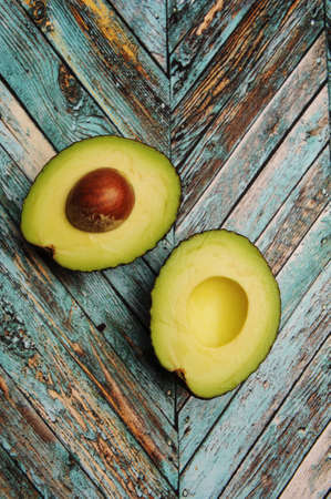 Avocado cut in half on turquoise wooden background, top view, vertical