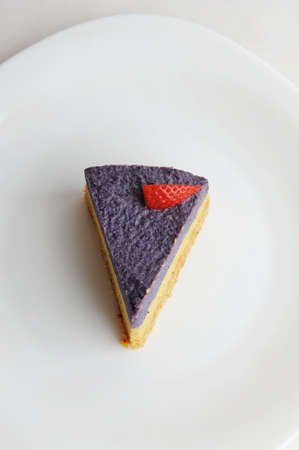 Raw vegan blueberry cake on a white background. Garnished with fresh strawberry. Top view, copy...