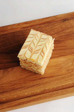 Slice of traditional Hungarian and Austrian Esterhazy cake on wooden board, close-upの写真素材