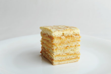 Slice of honey layer cake on white plate. Side view. Layer cake, close up