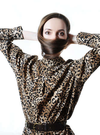 Long hair wrapped around the face like a mask. Fashion hairstyle concept. The model is wearing a leopard dress. Studio photo on whiteの写真素材