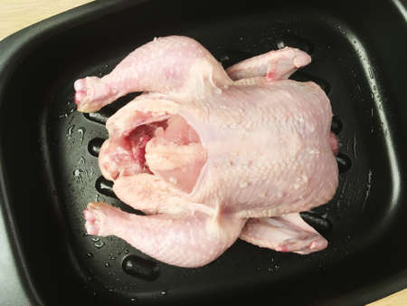 Whole raw chicken sprinkled with coarse sea salt on baking sheet before roastingの写真素材