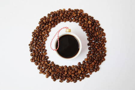 Christmas New Year coffee concept. Cup of black espresso coffee decorated with christmas tree ball. In round frame made of coffee beans. On white backgroundの写真素材